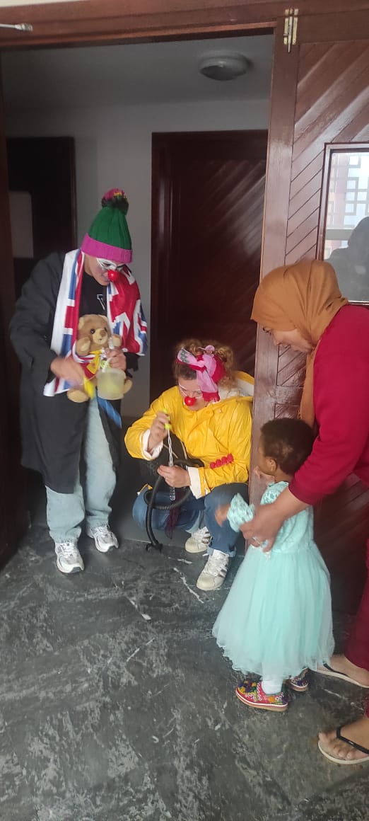 Clown offrant un doudou à un enfant lors d'une déambulation à domicile