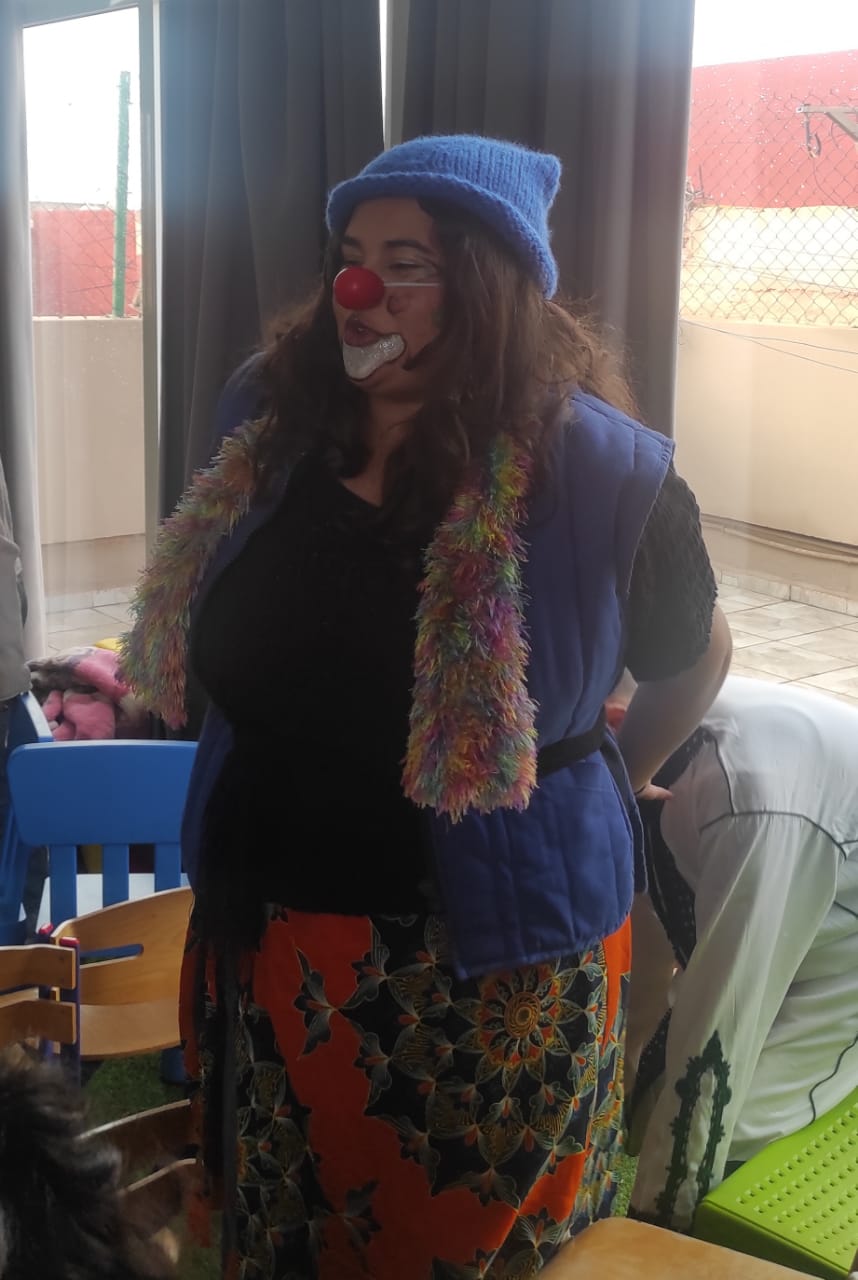 Clown en costume avec nez rouge et boa coloré lors d'une animation
